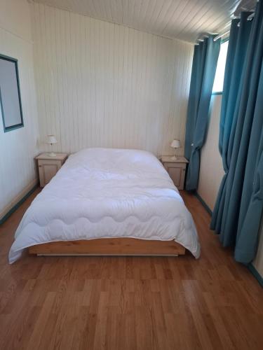 chalet cosy في لو كاستليت: غرفة نوم بسرير كبير مع ستائر زرقاء