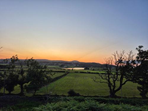 a sunset over a field with trees in a field at Culdaff Estate Glamping in Culdaff
