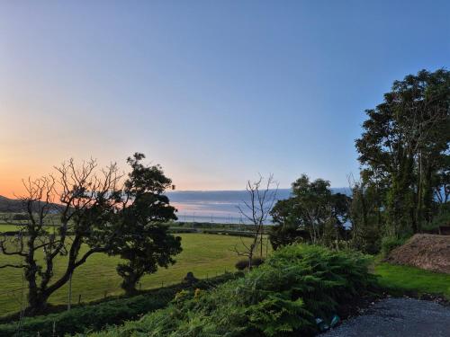 a view of a field with trees and a sunset at Culdaff Estate Glamping in Culdaff