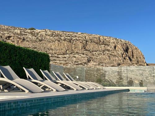 eine Reihe von Stühlen neben einem Pool in der Unterkunft R Lapsi Guesthouse in Siġġiewi