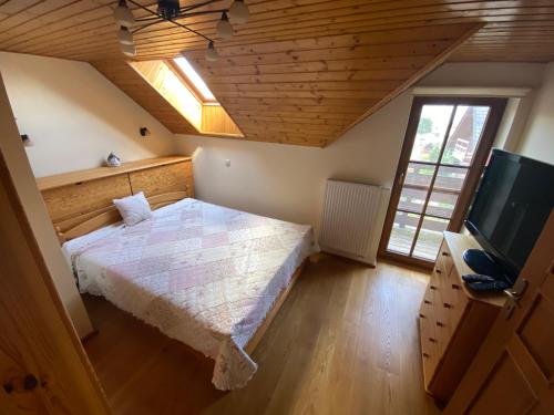 a bedroom with a bed and a flat screen tv at Chata Snowland in Valča