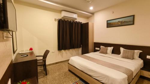 a hotel room with a bed and a desk and a television at Hotel Udaipur Stay at Prime Location in Udaipur