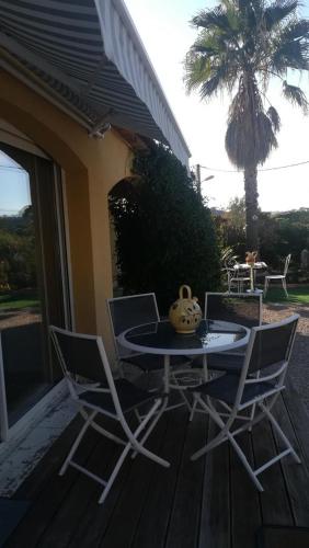 a table and chairs on a porch with a table and a vase at Gite hubert in Vidauban