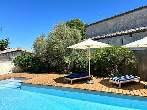 une piscine avec deux chaises et un parasol dans l'établissement La Bohème, à Galgon