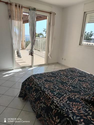a bedroom with a bed and a large sliding glass door at Leu doux bruit des vagues in Saint-Leu
