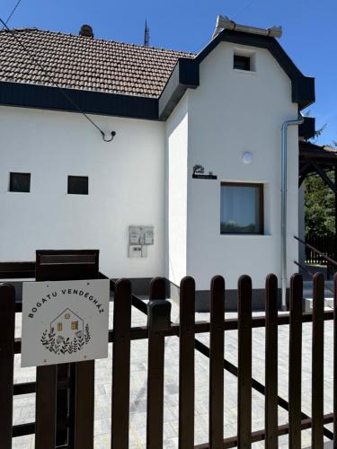 a sign on a fence in front of a white building at Bogatu Vendégház in Bogács