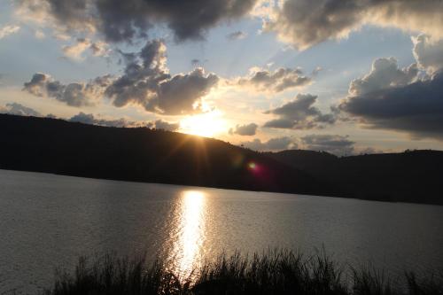 a sunset over a lake with the sun setting at Nyamunyonyi Lake Resort in Kabale