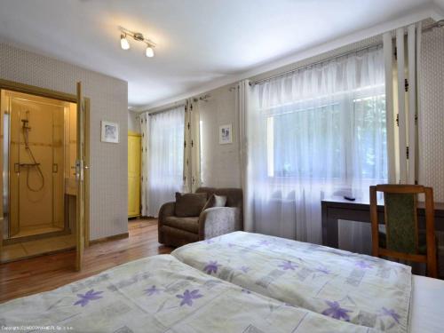 a bedroom with a bed and a chair and a window at Dworek Leśny in Kudowa-Zdrój