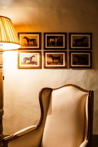 a room with a chair and a lamp and pictures of horses at Podere Dell'Arco Country Charme in Viterbo
