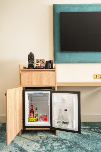 an open refrigerator in front of a tv at Crowne Plaza Gerrards Cross by IHG in Beaconsfield