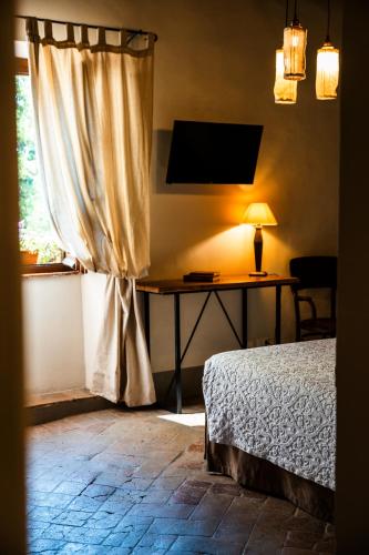 a bedroom with a bed and a desk with a window at Podere Dell'Arco Country Charme in Viterbo