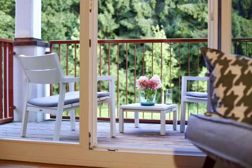 two chairs and a table with a vase of flowers on a porch at Waldhotel Stuttgart in Stuttgart