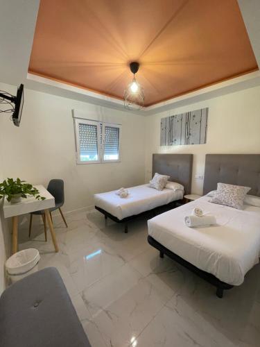 a room with two beds and a table and a room with two beds at La Villa del Sastre in Vélez-Málaga
