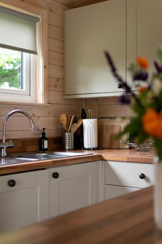 a kitchen with white cabinets and a sink at Kingfisher Lodge Riverdale in West Tanfield