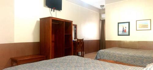 a bedroom with two beds and a cabinet and a tv at Hotel Playa Bonita Tela in Tela