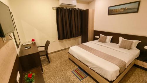 a bedroom with a bed and a desk and a television at Hotel Udaipur Stay at Prime Location in Udaipur