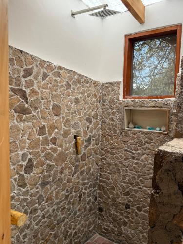 a bathroom with a stone wall with a shower at Sweta Takawiri island Shamba house in Takawiri Island