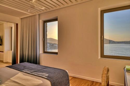 a bedroom with a bed and two windows at Avant Mar Paros in Naousa