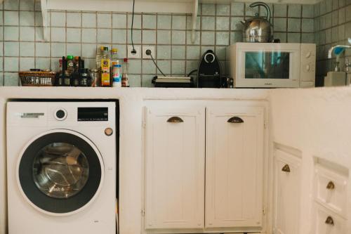a kitchen with a washing machine and a microwave at Dinora Villa in Agios Ioannis Tinos