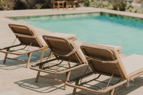 three chairs sitting next to a swimming pool at Dinora Villa in Agios Ioannis Tinos