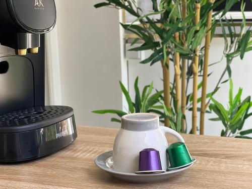 une tasse sur une table à côté d'une cafetière dans l'établissement Appart Jardin Lac Casino Enghien Les Bains 15 min Paris, à Soisy-sous-Montmorency