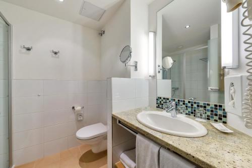 a bathroom with a sink and a toilet and a mirror at ROBINSON Landskron in Landskron