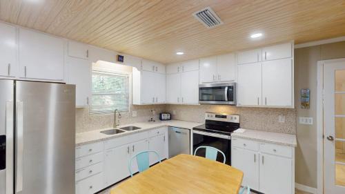 a kitchen with white cabinets and a wooden ceiling at BEACHY SISTERS B Duplex in Jekyll Island