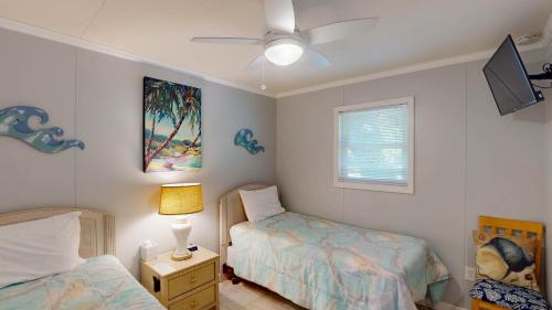 a bedroom with two beds and a lamp and a window at BEACHY SISTERS B Duplex in Jekyll Island