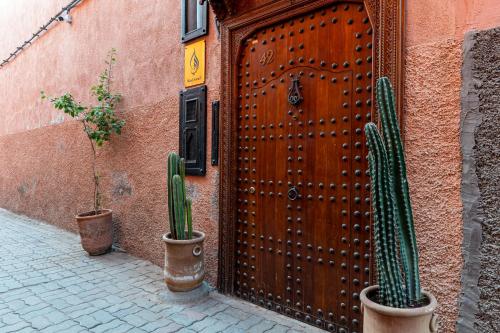 a wooden door with two cactuses in front of a building at Riad Asrari in Marrakech