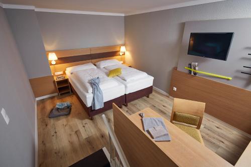 a bedroom with a bed and a table and a television at ROBINSON Landskron in Landskron