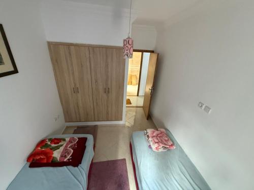 a small room with two beds and a cabinet at Spacious 80m 2 chambre in El Jadida