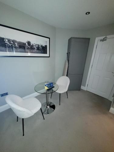 a room with two white chairs and a table and a door at Winckley Stays in Preston