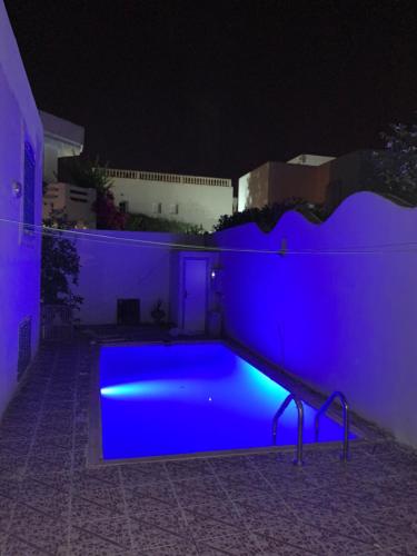 a swimming pool lit up in blue at night at Villa avec piscine au style Sibi Bou Saïd in Sousse