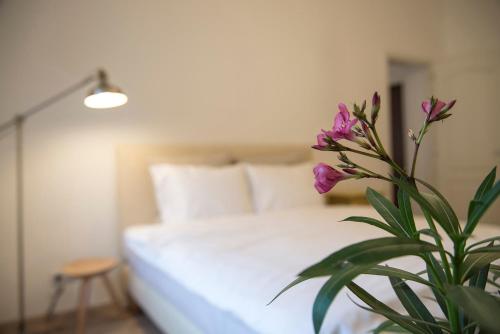 シビウにあるMovilei 15 Apartmentのベッドルーム1室(白いベッド1台、紫色の花の植物付)