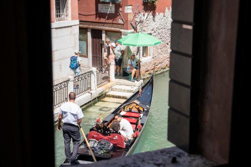 a group of people riding a gondola down a canal at Anzolo Palace - Rooms & Apartments in Venice