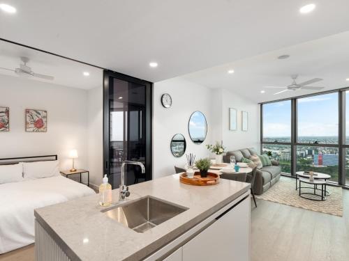 a bedroom with a bed and a kitchen with a sink at QW Riverside Luxe Apartments by Independent Host in Brisbane