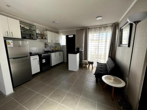 a kitchen with a refrigerator and a table and a couch at Casa en Valles del Sauce II in Coquimbo