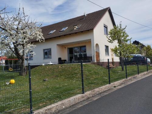 a white house with a fence in front of it at Ferienwohnung Sulzfeld - Liebevoll eingerichtete Ferienwohnung in Sulzfeld im Grabfeld in Sulzfeld (im Grabfeld)