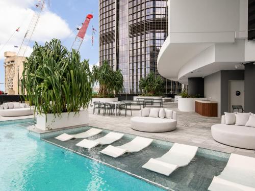 a pool with lounge chairs and tables on a building at QW Riverside Luxe Apartments by Independent Host in Brisbane