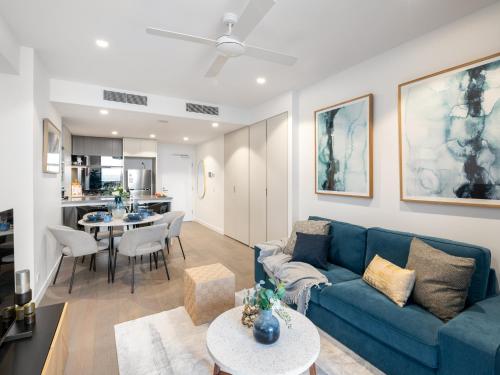 a living room with a blue couch and a table at QW Riverside Luxe Apartments by Independent Host in Brisbane