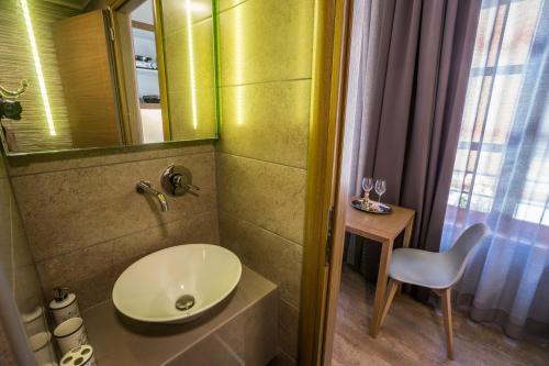 a bathroom with a sink and a mirror and a chair at 11City Rooms in Chania Town