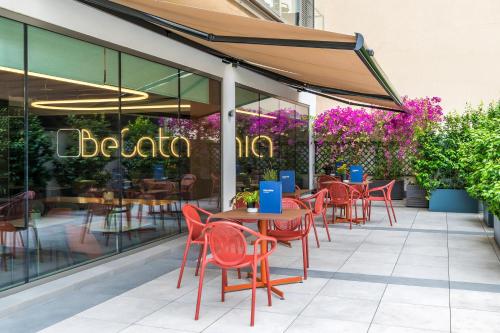 a restaurant with red chairs and tables on a patio at Catalonia Gran Vía Bilbao in Bilbao
