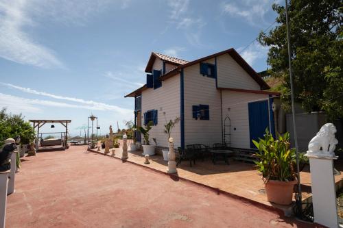 a white house with blue windows and a patio at Chalet, breathtaking sea view with large jacuzzi in Almuñécar