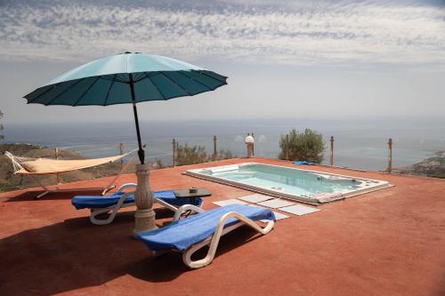 two chairs and an umbrella next to a swimming pool at Chalet, breathtaking sea view with large jacuzzi in Almuñécar