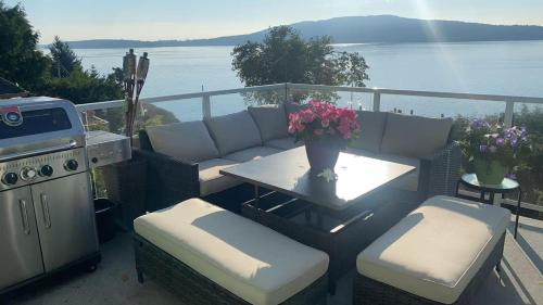 a patio with a table and chairs and a view of the water at Beachbreeze Panoramic Oceanview 4BR 3BA Romantic Sunrise & Celestial Views in Mill Bay