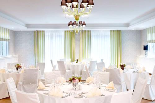 a room with white tables and white chairs and a chandelier at Waldhotel Stuttgart in Stuttgart