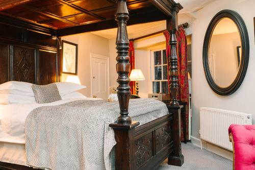 a bedroom with a canopy bed and a mirror at The Castle Inn in Castle Combe