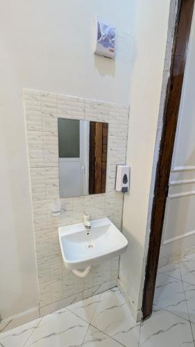 a bathroom with a white sink and a mirror at Mielz Apartment in Dar es Salaam