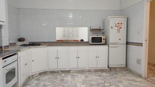 a white kitchen with a refrigerator and a microwave at Villa avec piscine au style Sibi Bou Saïd in Sousse