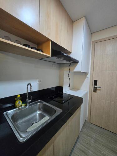 a kitchen with a stainless steel sink and a door at 2 Bedroom Suite in SM Marilao - Cheer Residence in Marilao